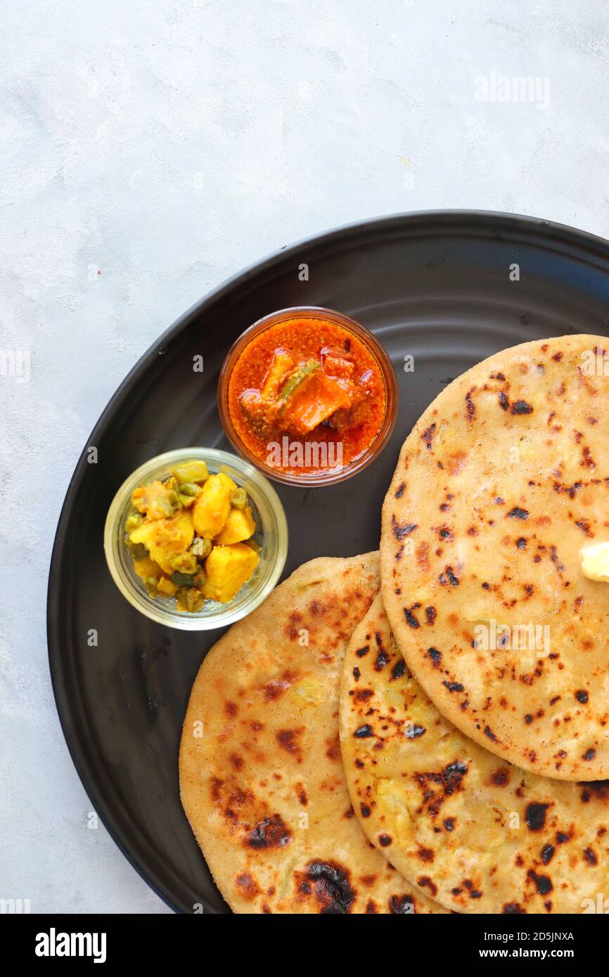 Aloo / Alu Paratha oder indisches Potato gefülltes Fladenbrot. Serviert mit Butter zum Frühstück, Gurke und Masala Kartoffeln unter mit Masala Tee / Chai. Stockfoto