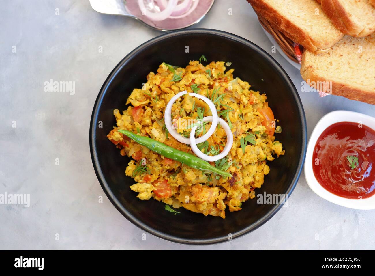 Indisches Frühstücksgericht: Parsi Akuri oder Anda Bhurji oder indische, würzige Rühreier, serviert mit geröstetem braunem Brot und Ketchup. Berühmte indische Street Food Stockfoto