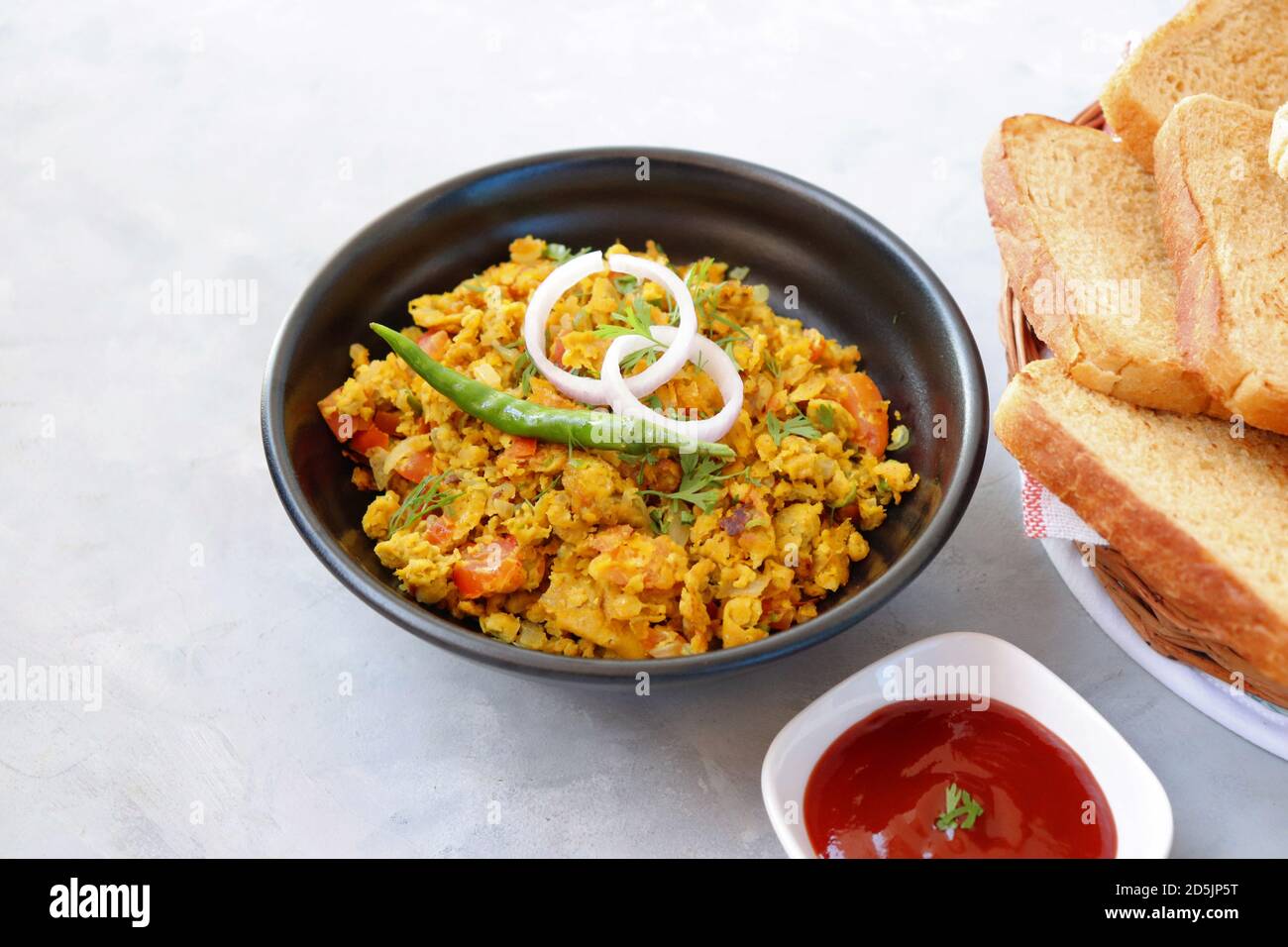 Indisches Frühstücksgericht: Parsi Akuri oder Anda Bhurji oder indische, würzige Rühreier, serviert mit geröstetem braunem Brot und Ketchup. Berühmte indische Street Food Stockfoto