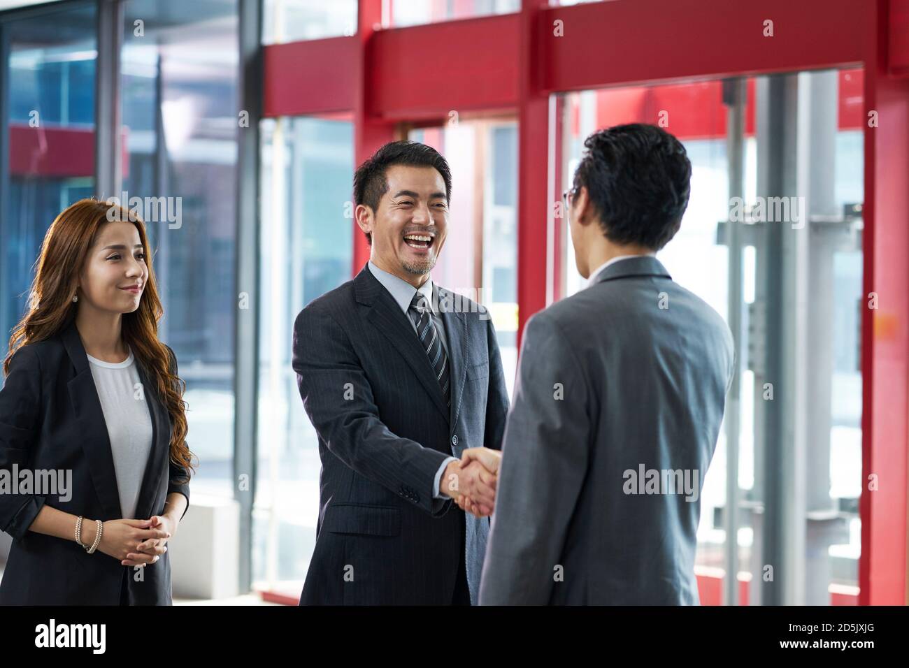 asiatische Führungskräfte schütteln die Hände mit Kunden im Aufzug besuchen Halle des modernen Bürogebäudes Stockfoto