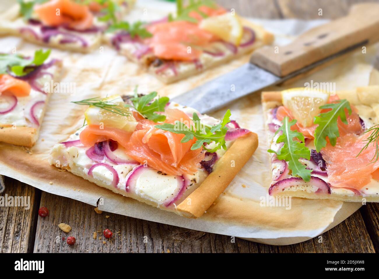 Flambienkuchen aus dem Elsass mit geräuchertem Lachs und Rucola-Blättern Stockfoto