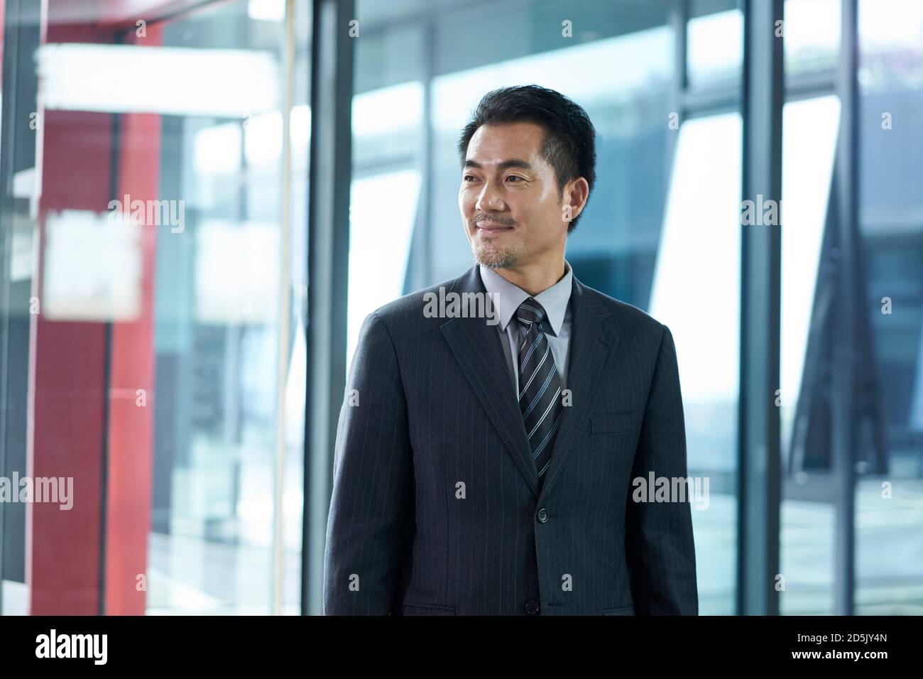 Erfolgreicher asiatischer Geschäftsmann Corporate Executive, der in der Firmenlobby herumläuft Stockfoto