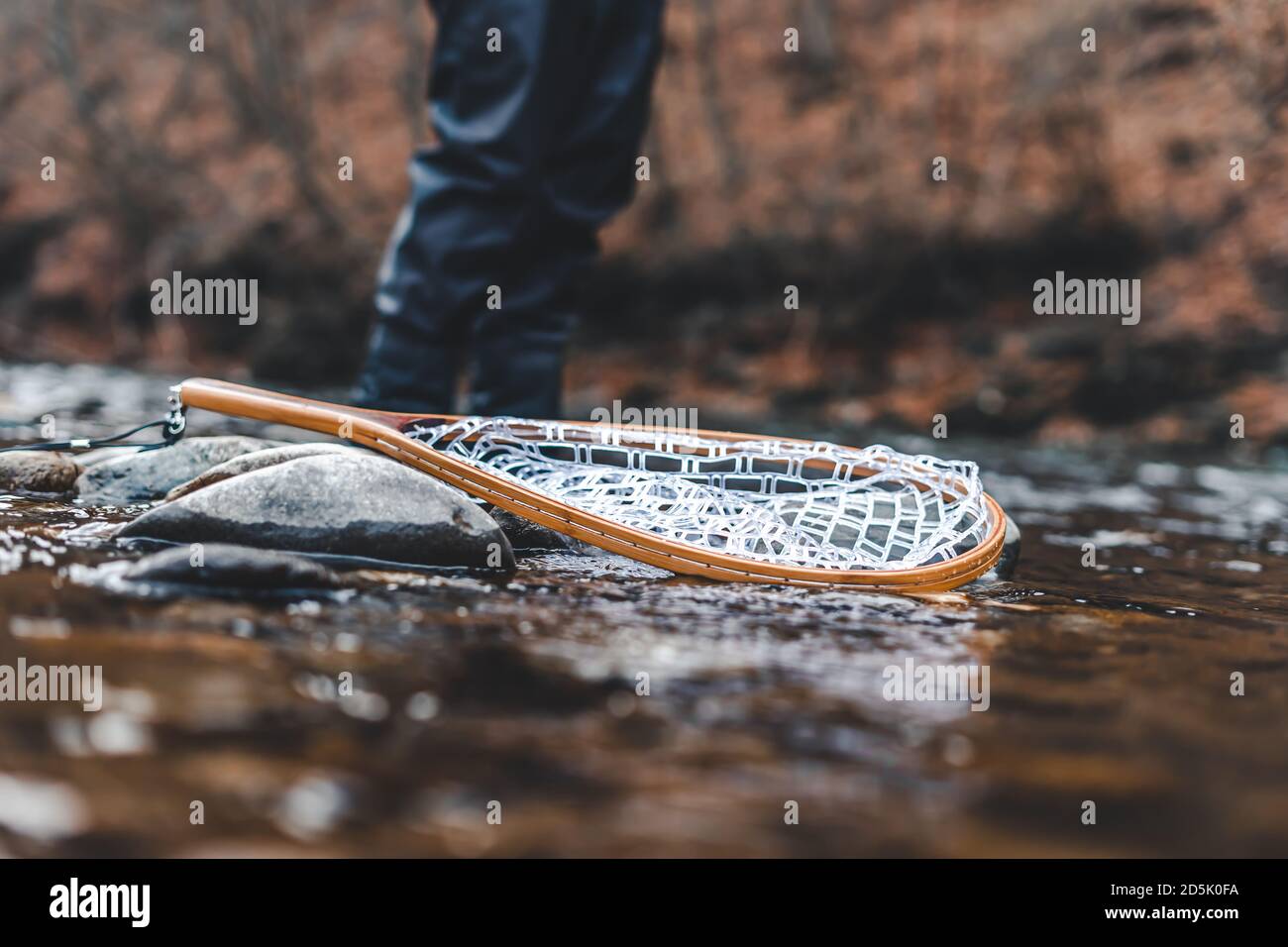 Fischernetz auf Felsen im Fluss mit verwackelte Fischer hinter. Stockfoto