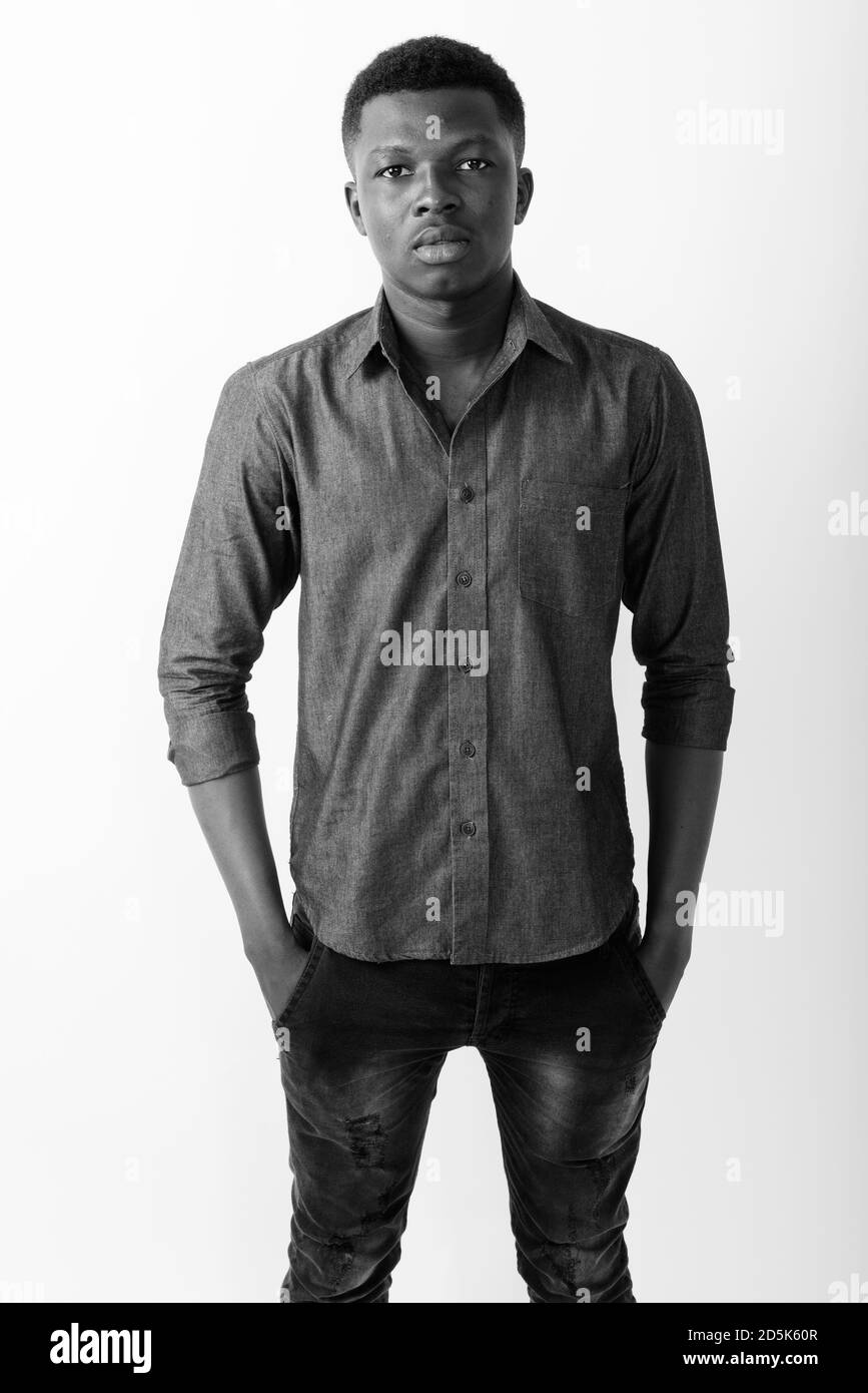 Studio shot von jungen schwarzen afrikanischen Mann stand mit den Händen auf Taschen vor weißem Hintergrund Stockfoto