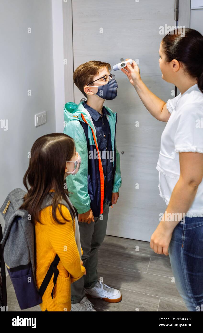 Mutter überprüft die Temperatur ihres Sohnes, bevor sie zur Schule geht Stockfoto