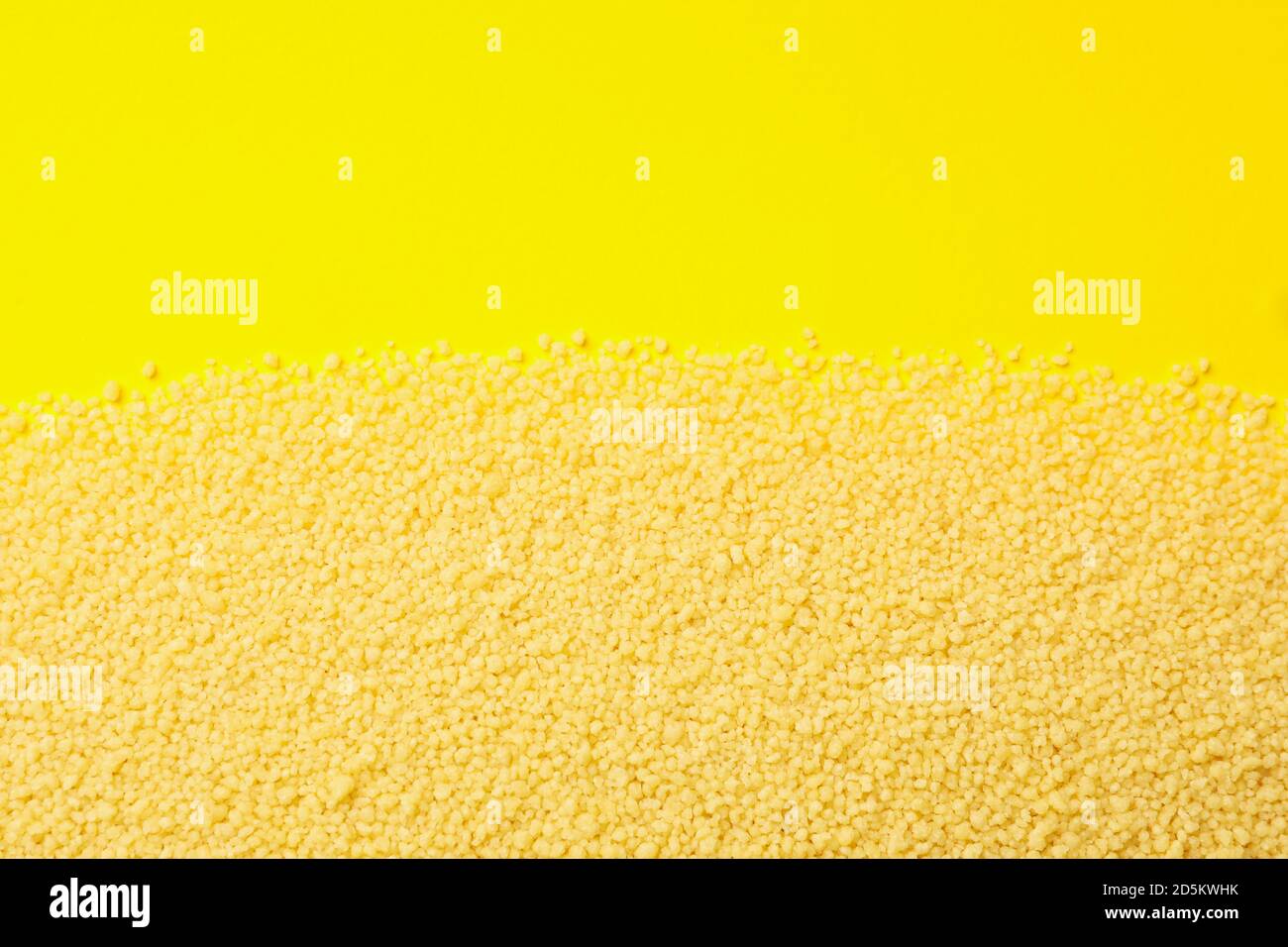 Roher Couscous auf gelbem Hintergrund, Platz für Text Stockfoto