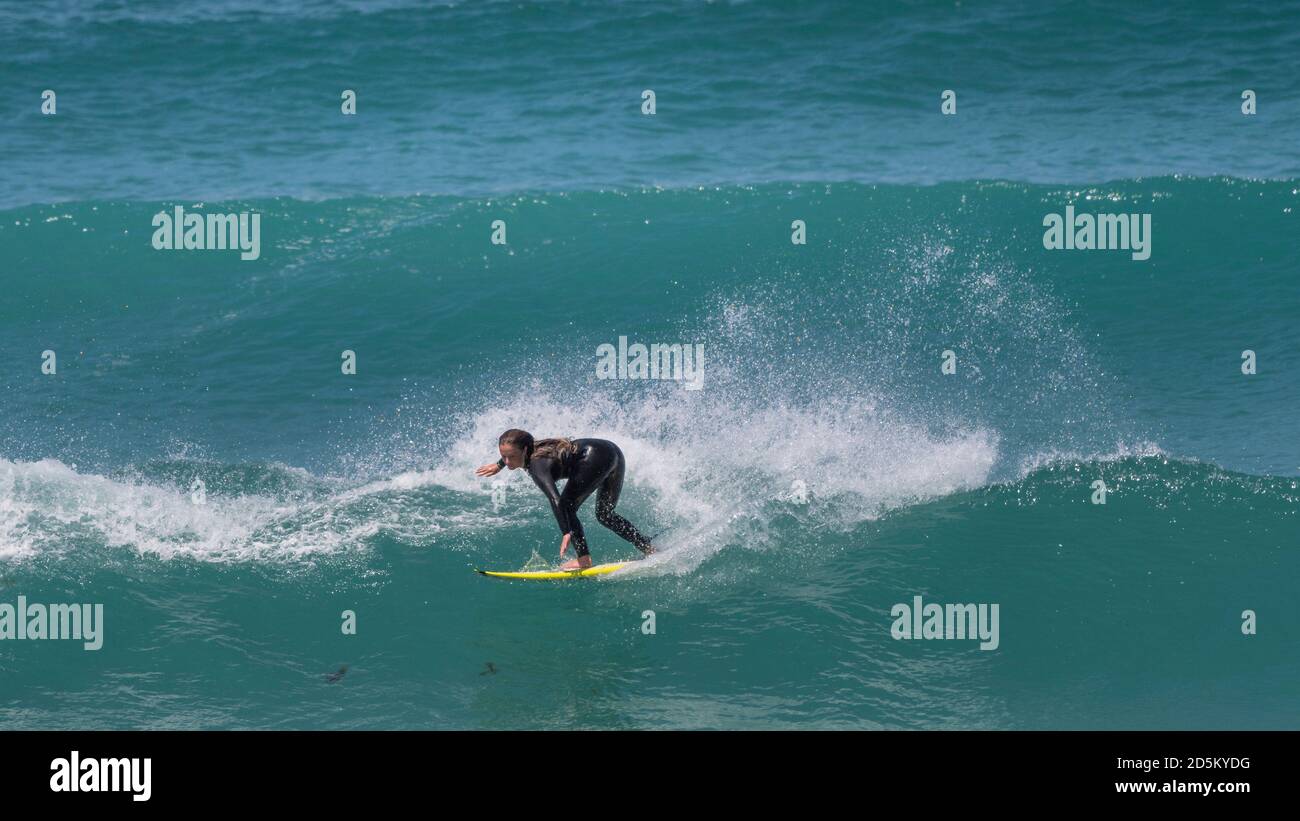 Spektakuläre Action als Surferin reitet eine Welle am Fistral in Newquay in Cornwall. Stockfoto