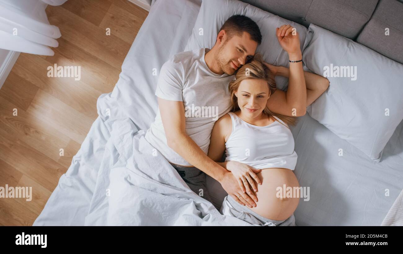 Happy Young couple Kuscheln zusammen im Bett, junge Frau ist schwanger und  liebevolle Partner berührt und streichelt ihren Bauch zärtlich. Die Sonne  Scheint. Oben Stockfotografie - Alamy
