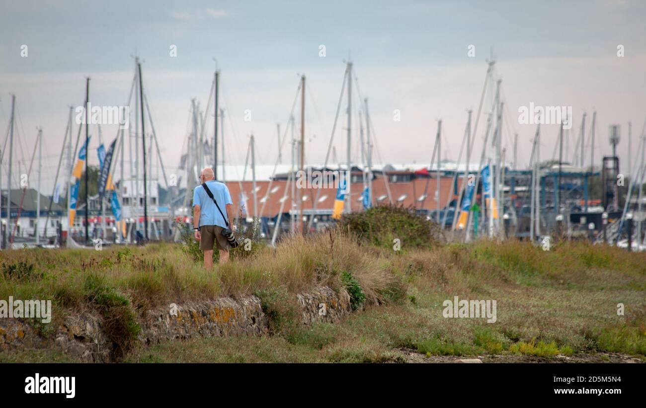 Ein Vogelbeobachter auf der Suche nach seinem nächsten Schuss auf einem Spaziergang an der Südküste von England. Küstenwanderfotograf Vogelbeobachter. Stockfoto