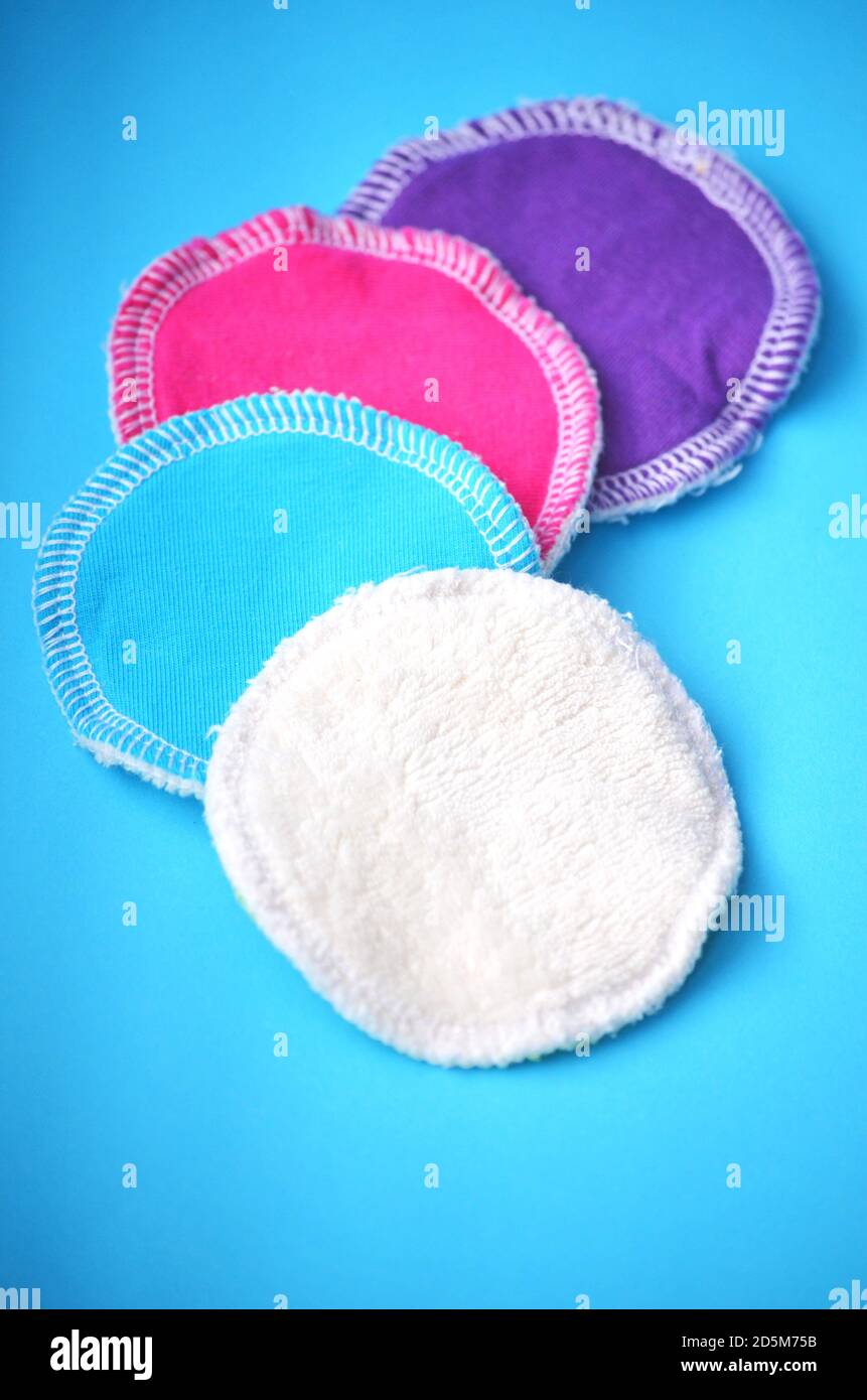 Vier wiederverwendbare waschbare Zero Waste Reinigungspads aus Bio-Baumwolle für Make-up Entfernung in weiß blau lila und rosa Farbe Auf einem pastellblauen Hintergrund Stockfoto