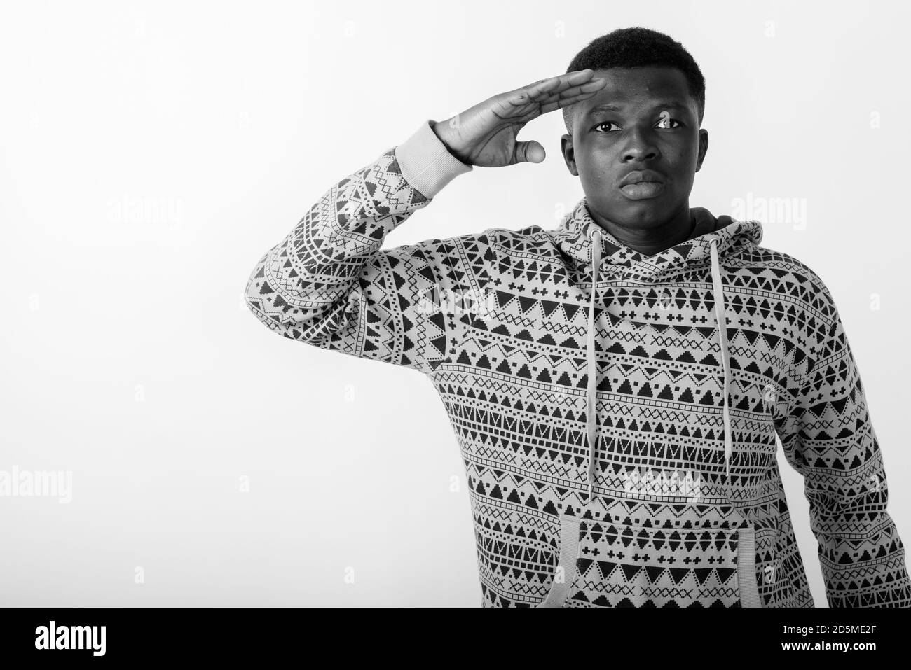 Studio shot von jungen schwarzen afrikanischen Mann salutierte vor weißem Hintergrund Stockfoto