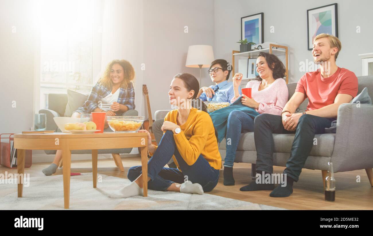 Zu Hause Diverse Gruppenfreunde, die gemeinsam Fernsehen, Snacks essen und Getränke trinken. Sie sehen wahrscheinlich Sport Spiel, Film oder Sitcom TV-Show Stockfoto