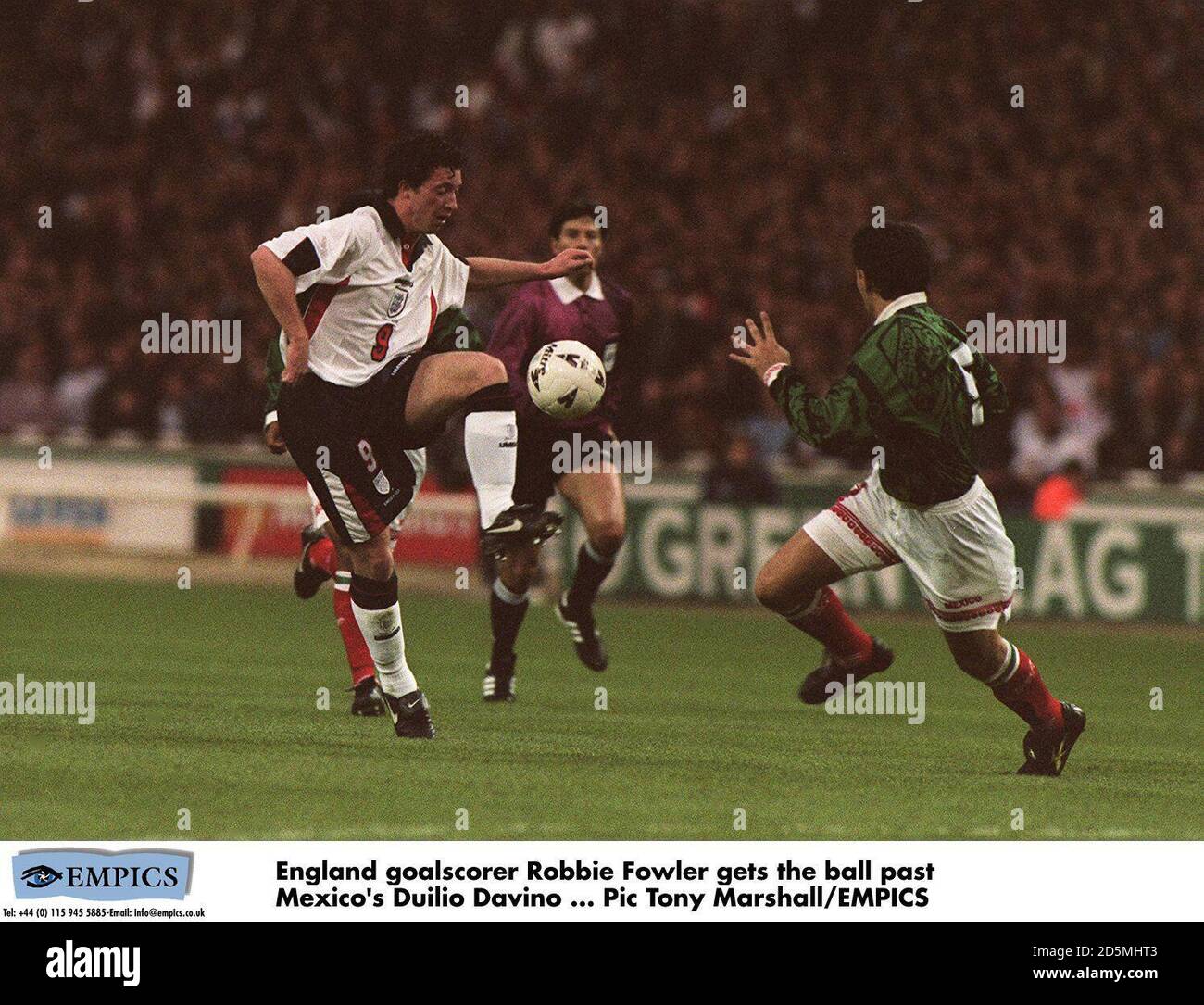 England Torschütze Robbie Fowler holt den Ball an Mexikos Duilio vorbei Davino Stockfoto