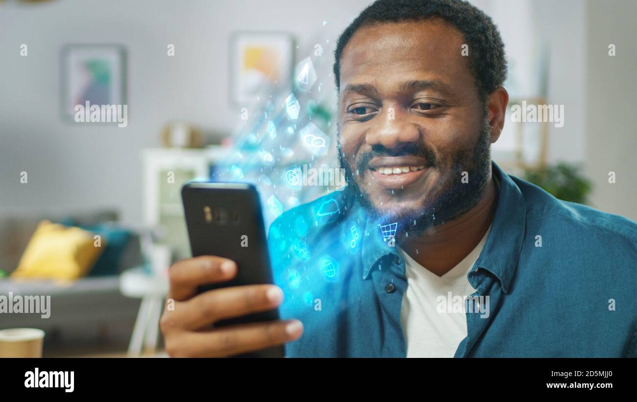 Visuelle Wirkung von Verbindung und Surfen im Web mit illustrativen Symbolen und Symbolen. Schöner schwarzer Mann verwendet Smartphone in seinem Wohnzimmer. Durchsuchen Stockfoto