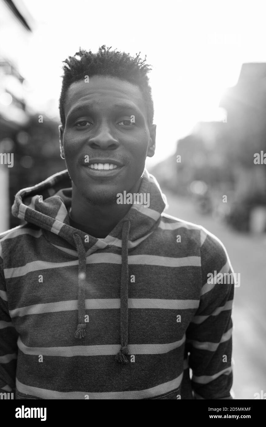 Junge glücklich Slim schwarz afrikanischer Mann lächelnd im Freien Stockfoto