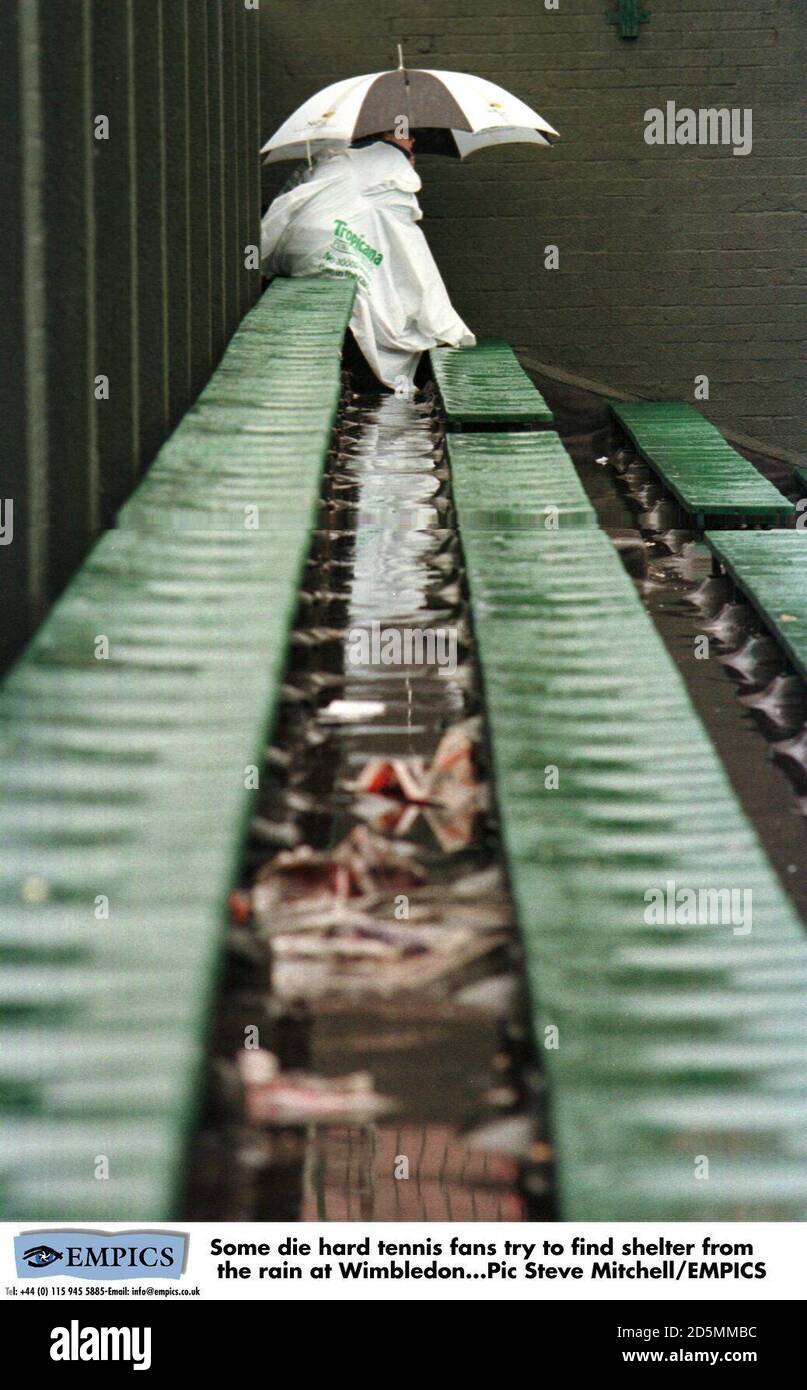 Einige sterben hart Tennis-Fans versuchen, Schutz vor zu finden Der Regen in Wimbledon Stockfoto