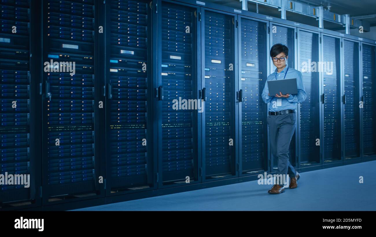 Im modernen Rechenzentrum: IT-Techniker, die mit Server-Racks arbeiten, nutzt Laptop für Wartung und Diagnose. Überprüfen der Systemstabilität Stockfoto