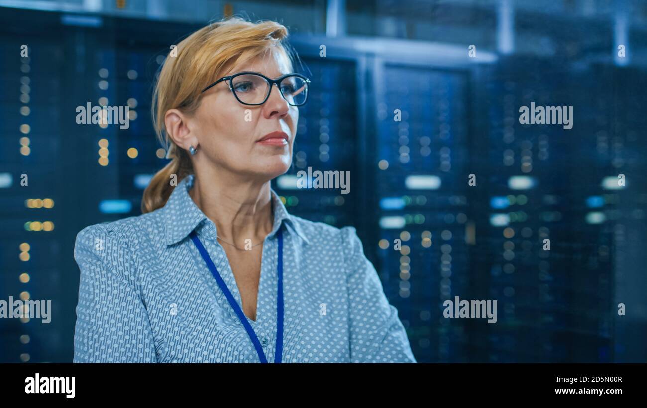 Porträt einer schönen leitenden IT-Technikerin im modernen Rechenzentrum. Im Hintergrund funktionierende Server-Racks mit blinkenden LED-Anzeigen. Stockfoto