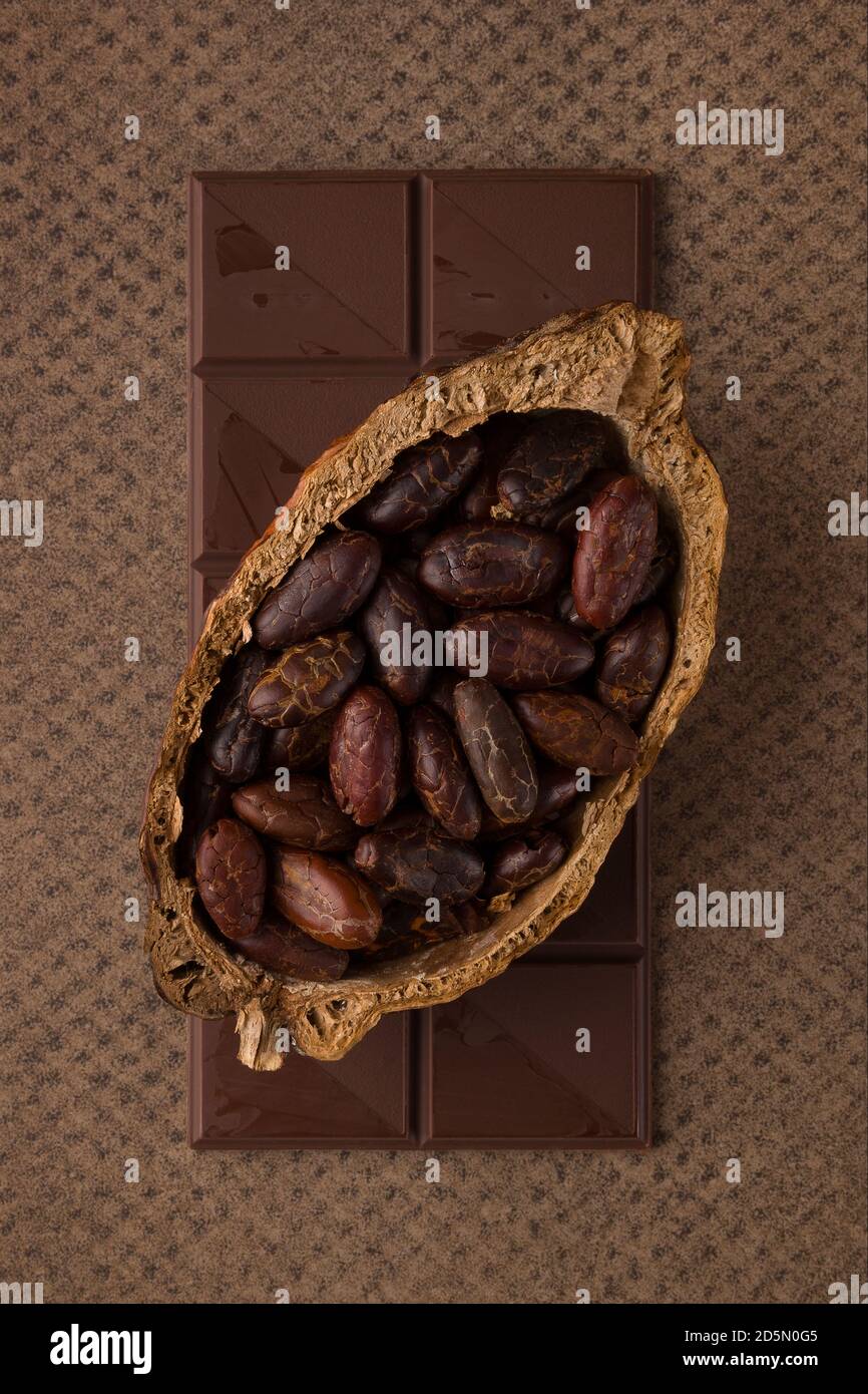Schokoladenriegel und Kakaobohnen auf braunem Hintergrund. Luxuriöse dunkle Stimmung Hintergrund. Stockfoto