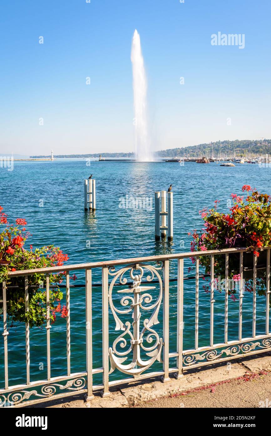 Der Jet d'Eau Wasserstrahlbrunnen in der Bucht von Genf, Schweiz, mit einem schmiedeeisernen Geländer mit Anker und Topfblumen an einem sonnigen Sommertag. Stockfoto