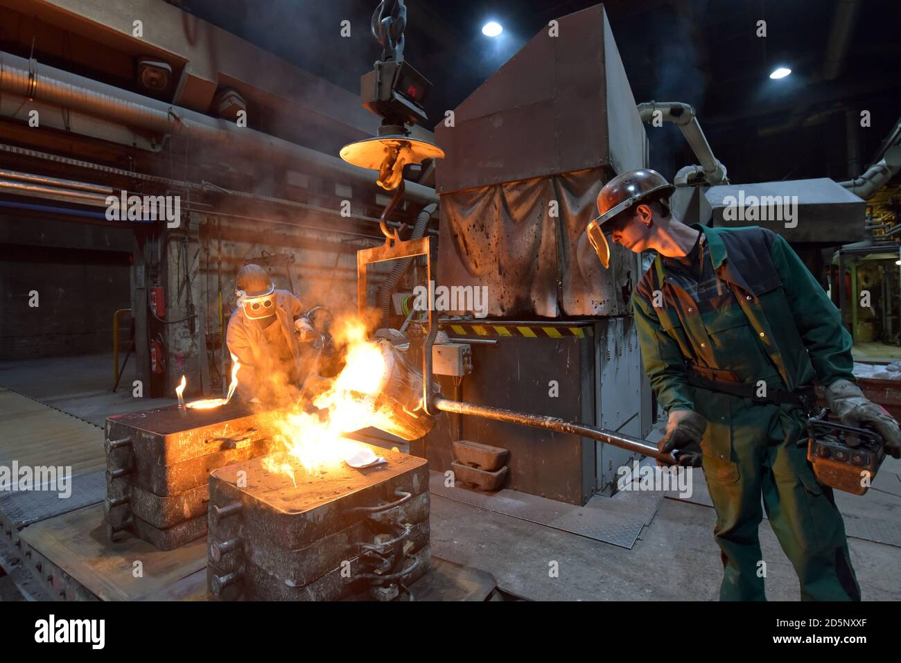 Arbeitnehmer in einer Gießerei gießen ein Werkstück aus Metall - Sicherheit bei der Arbeit und Teamarbeit Stockfoto