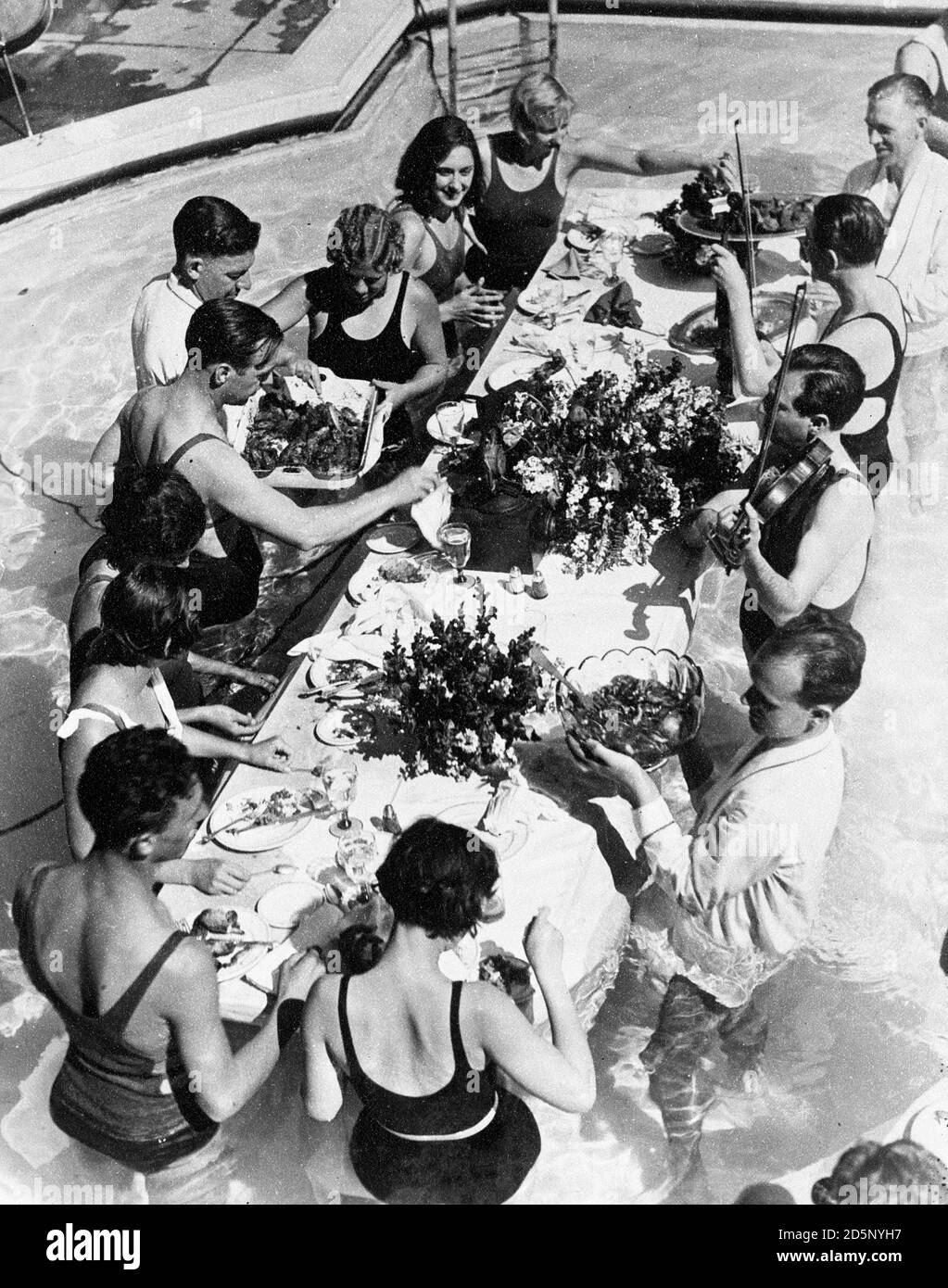 Ein Bankett wurde im Huntingdon Pool in Pasadena, Kalifornien, zu Ehren des Weltrekord brechenden Frauen Staffelteams gegeben. Das Bankett schwebte im Wasser und die Gäste essen ihr Essen stehend im Wasser. Die Szene, die im Vordergrund beginnt, L-R, sind Margaret Gardiner, Arthur smith, Josephine McKim, Jennie Cramer. Mitglieder des Staffelteams, H.J. Romer, Georgia Coleman, der amerikanische Tauchmeister, Olive Hatch und Marjorie Lowe. Stockfoto