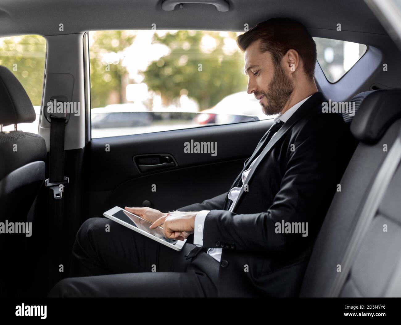 Wohlhabender Mann, der am digitalen Pad arbeitet, während er zum Flughafen geht Stockfoto