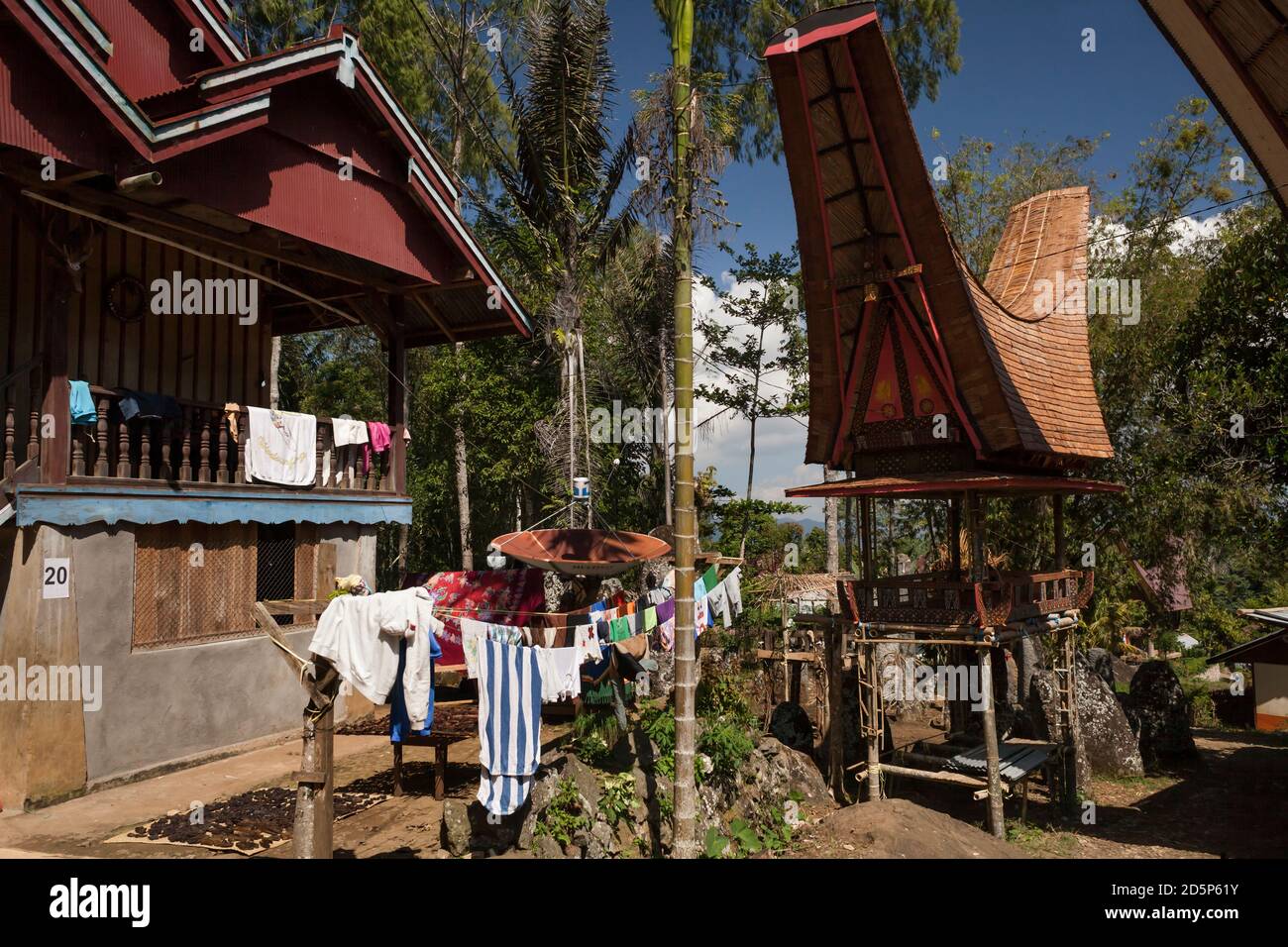 Horizontaler Blick auf das Äußere eines traditionellen Torajan-Hauses mit hängender Wäsche, einem Tongkonan und einer Parabolantenne im Dorf Buntu Lobo' Viesta Stockfoto