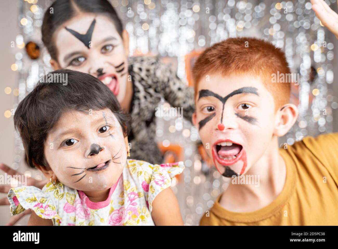 Gruppe von Kindern in Halloween-Kostümen gestikulierend und machen gruselige oder gruselige Gesichter auf dekorierten Hintergrund durch Blick in die Kamera. Stockfoto