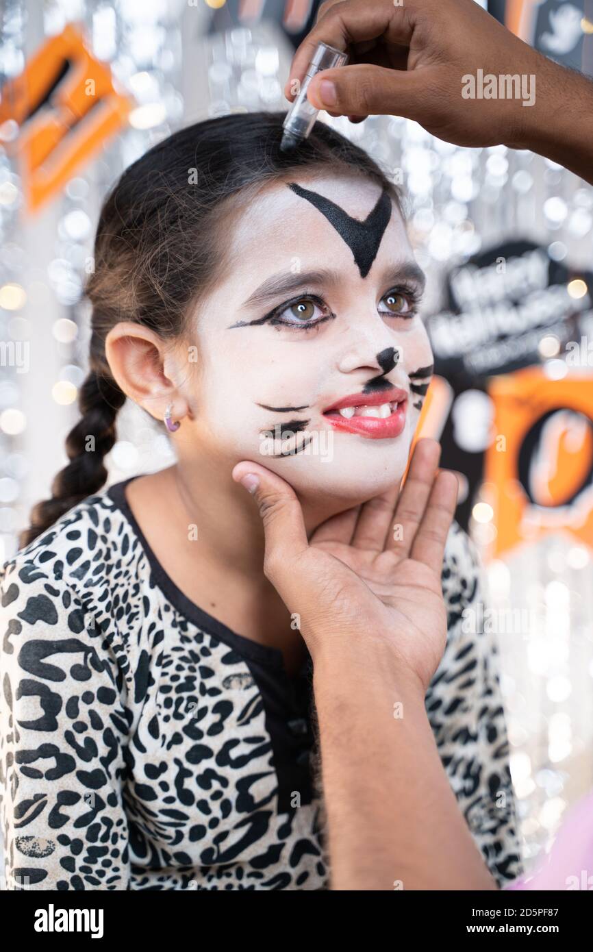 Elternteil hilft ihrer Tochter, sich bereit für Halloween durch Make-up - Konzept von Halloween, Urlaub und Kinderfest Feier und Stockfoto