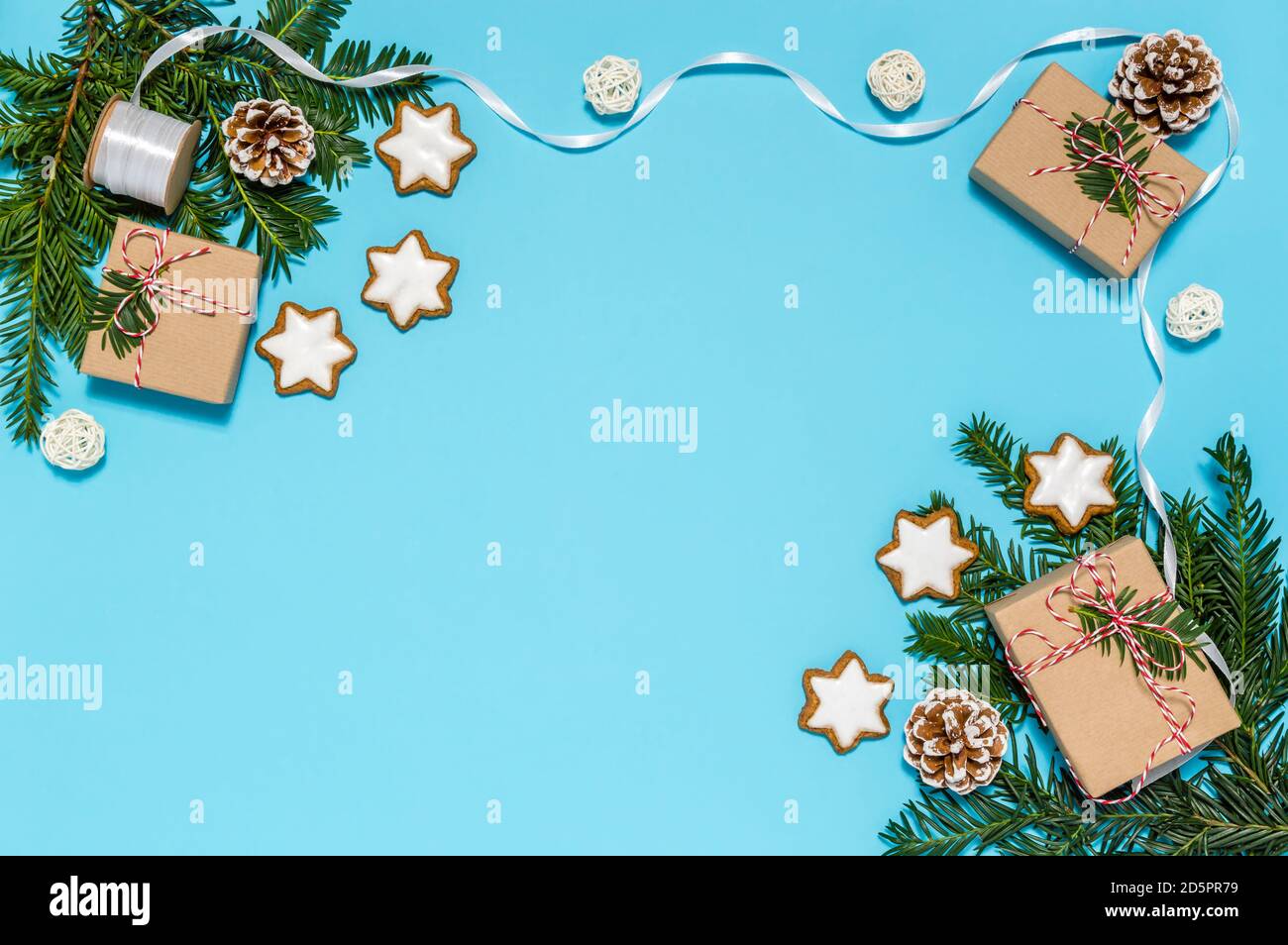 Plastikfreies Weihnachts-Flatlay mit handgefertigten Geschenkschachteln, Band und Feiertagsdekoration: Nadelbaum Zweig, Zapfen, Zimt Stern Cookies auf blau Stockfoto