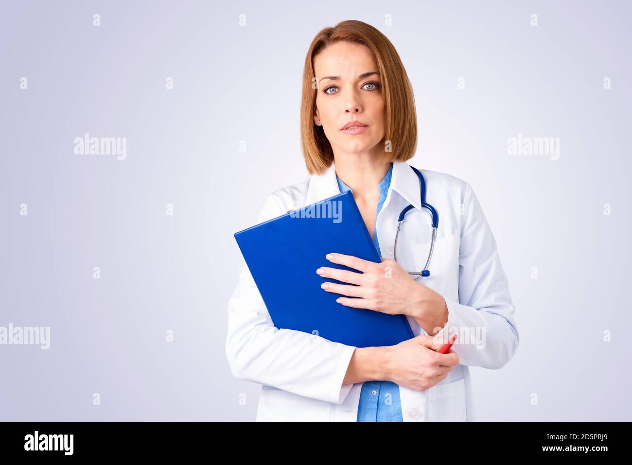 Studioportrait einer Ärztin, die Ordner in der Hand hält, während sie vor isoliertem Hintergrund steht. Speicherplatz kopieren. Stockfoto