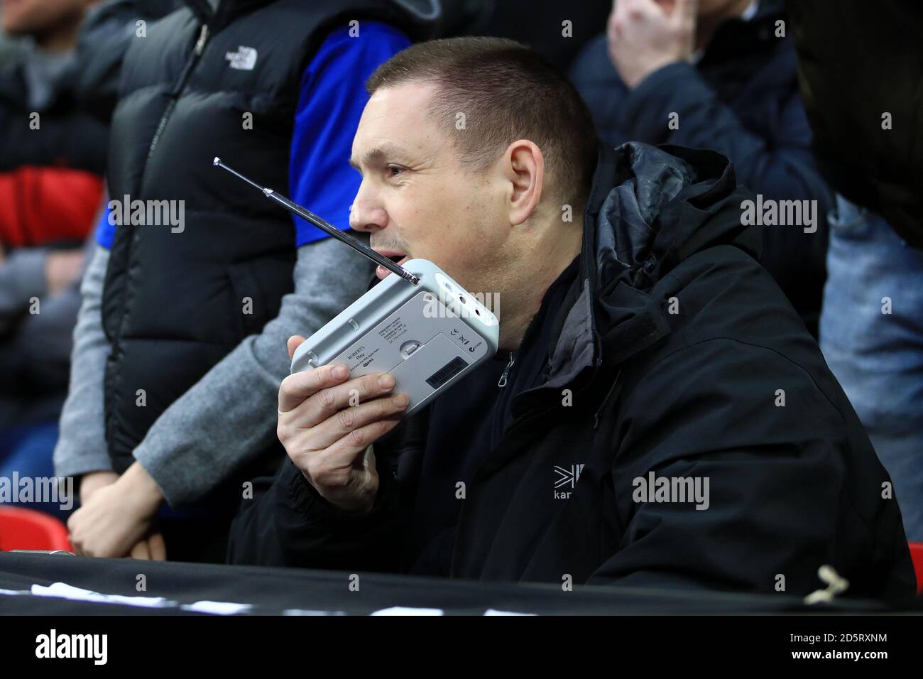 Ein Unterstützer an den Ständen beobachtet das Spiel beim Zuhören An ein tragbares Radio Stockfoto
