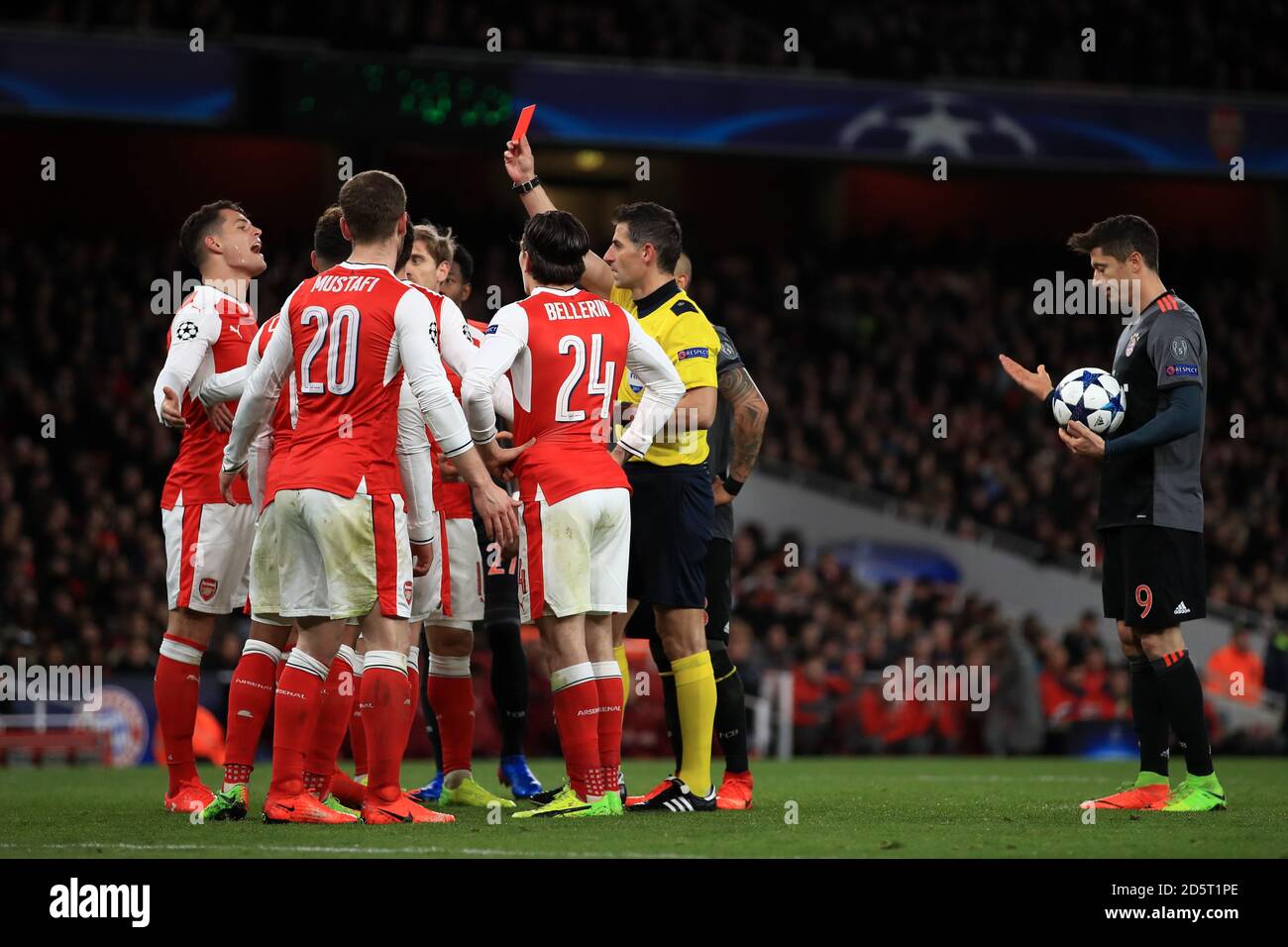 Schiedsrichter Tasos Sidiropoulos (rechts) zeigt Arsenals Laurent Koscielny (verdeckt) A Rote Karte nach einem Foul im Strafraum auf Bayern München Robert Lewandowski (rechts) Stockfoto