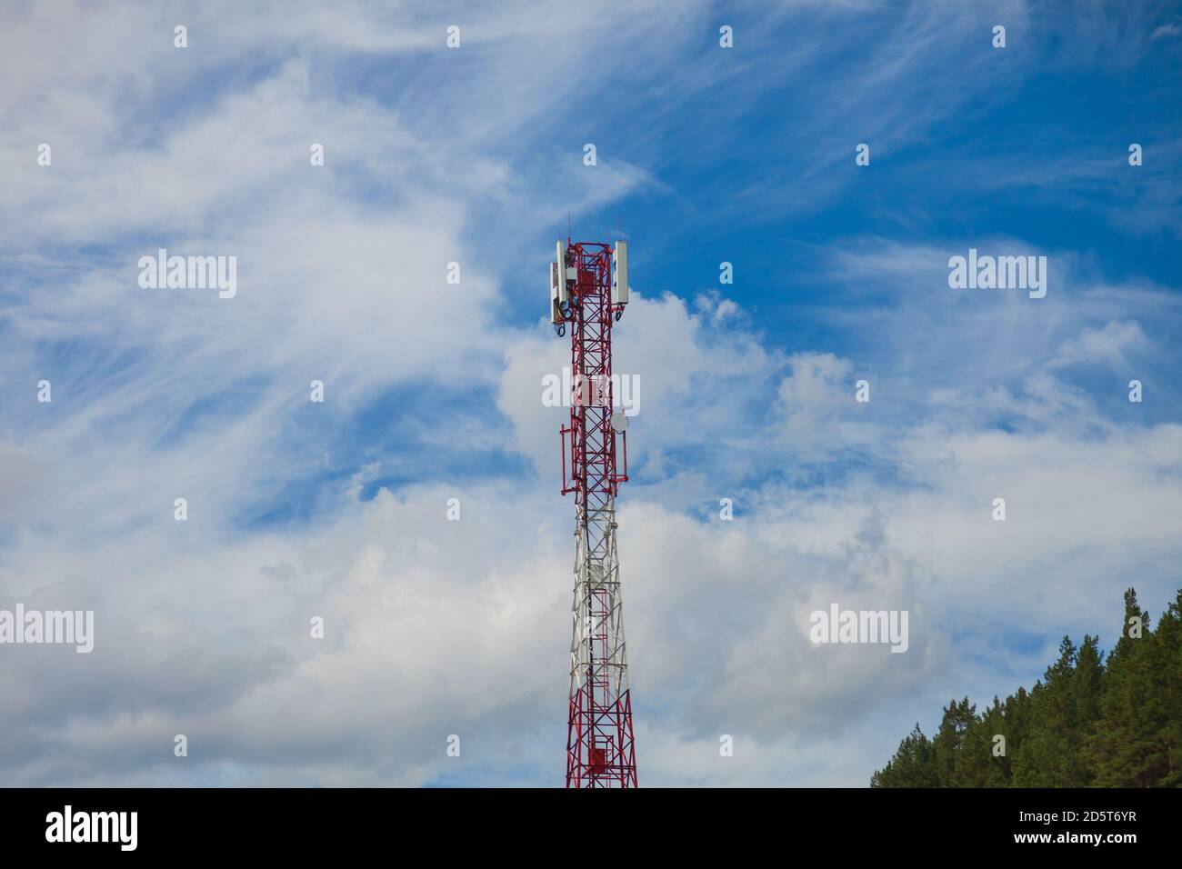 Ein Zellturm aus rot-weißem Metall in einem unzugänglichen Platz in den Altai-Bergen vor dem Hintergrund von Grün Nadelbäume für die Übertragung Stockfoto