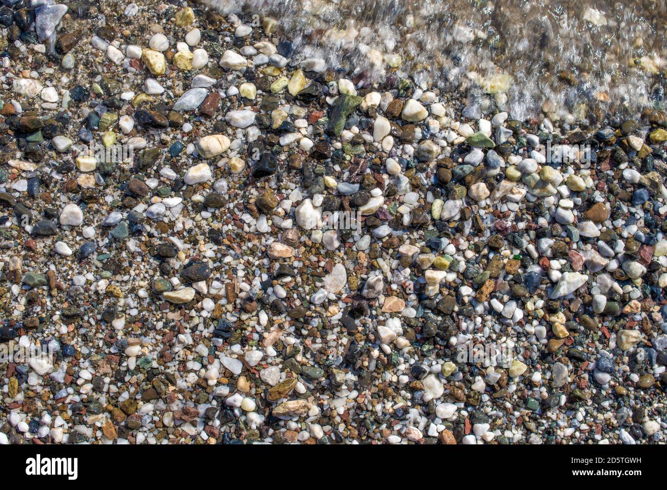 Kieselsteine und Schaum. Steine und Meer. Kieselsteine Steine Textur. Kleine Seesteine, Kies. Hintergrund. Texturen Stockfoto