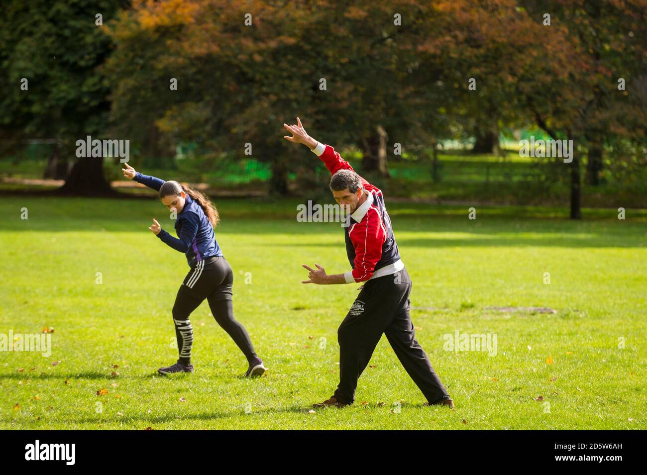 London, Großbritannien. 14. Oktober 2020. UK Wetter: Ein Paar übt Tai Chi, auch Tai Chi chuan genannt, als die Blätter auf Bäumen im Green Park beginnen, ihre Herbstfarbe zu nehmen. Ursprünglich als Kampfkunst im China des 13. Jahrhunderts entwickelt, wird Tai Chi heute weltweit als gesundheitsfördernde Übung praktiziert und verbindet tiefes Atmen und Entspannung mit fließenden Bewegungen. Gute Sonneneinbrüche im Frühjahr und Sommer, gefolgt von Regenfällen im September, lassen den diesjährigen Herbstlaub in diesem Jahr besonders eindrucksvoll erscheinen. Kredit: Stephen Chung / Alamy Live Nachrichten Stockfoto