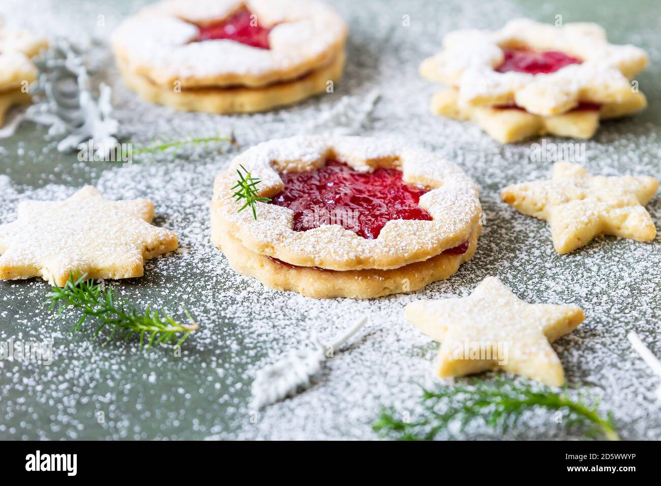 Traditionelle Linzer Weihnachtsplätzchen mit Himbeermarmelade auf grünem Hintergrund. Festliche Dekoration. Stockfoto