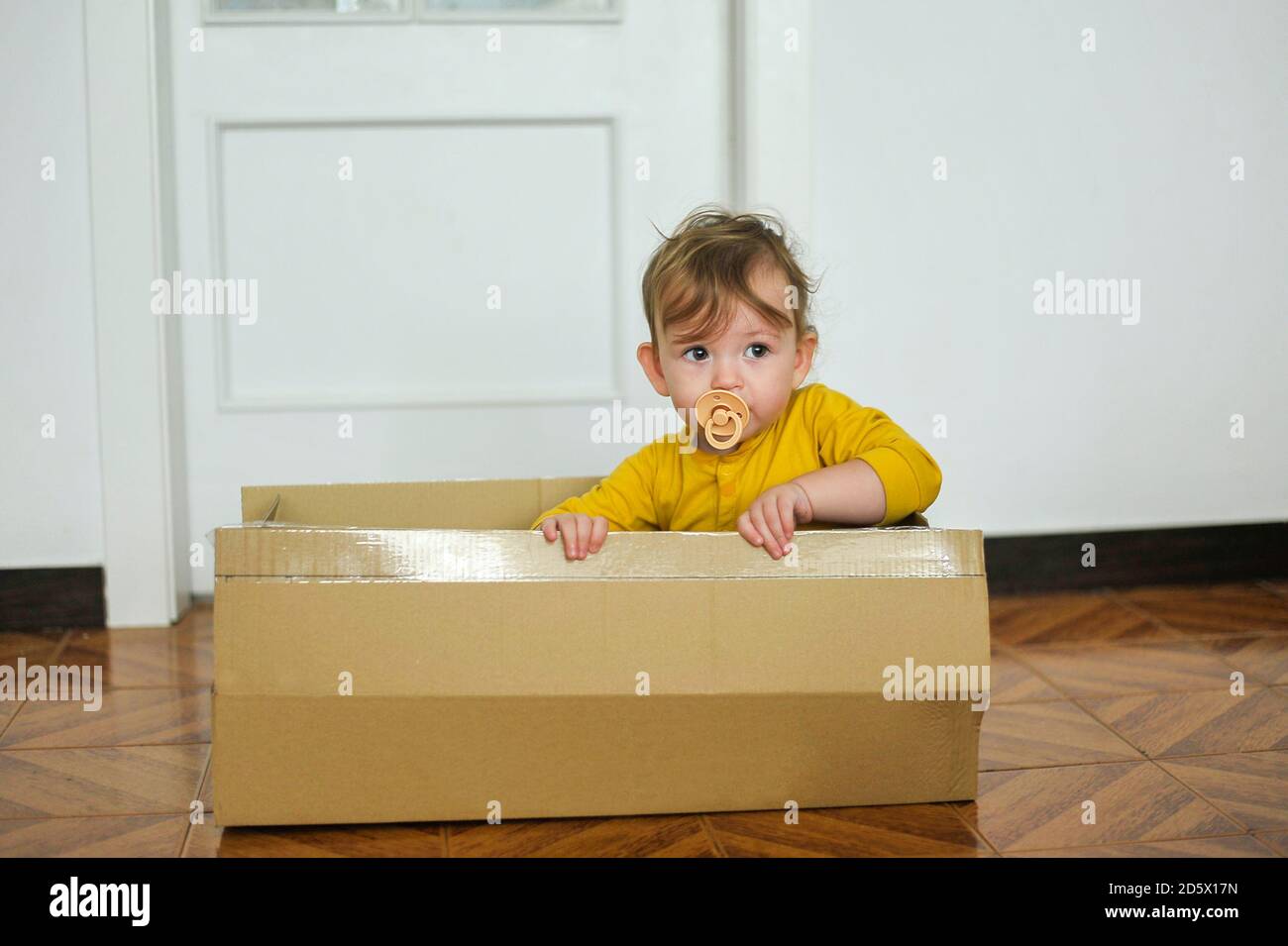 Baby spielt mit Pappkarton Stockfoto