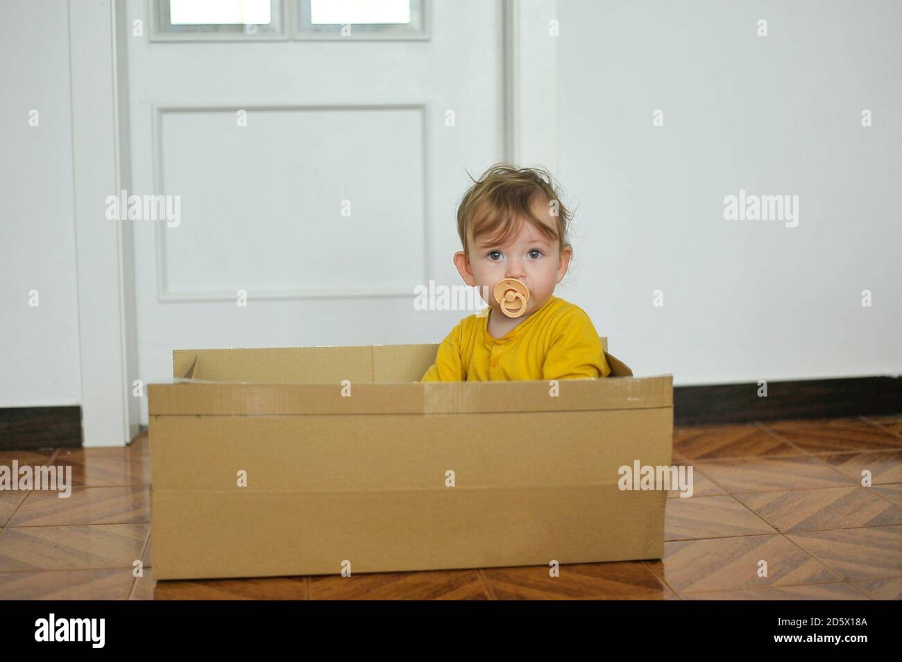 Baby spielt mit Pappkarton Stockfoto