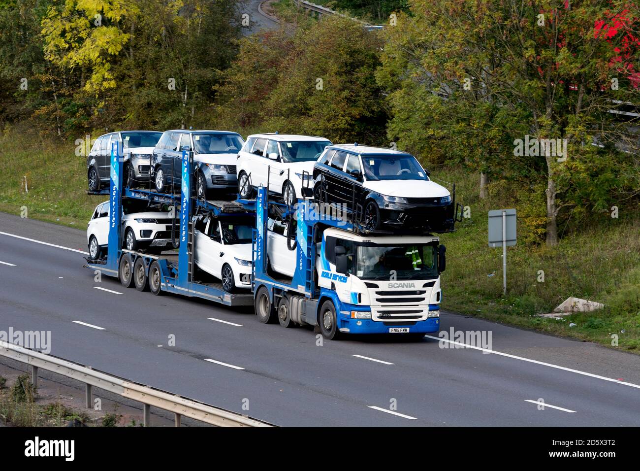 Ein mobiler Scania-Transporter mit neuen Land Rover Fahrzeugen auf der Autobahn M40, Warwickshire, Großbritannien Stockfoto