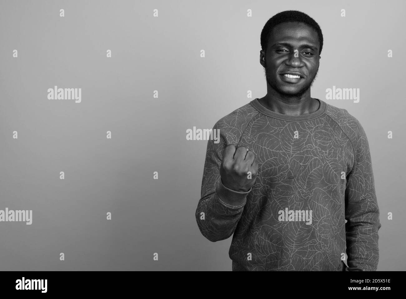 Junger afrikanischer Mann trägt langärmeliges Hemd vor grauem Hintergrund Stockfoto
