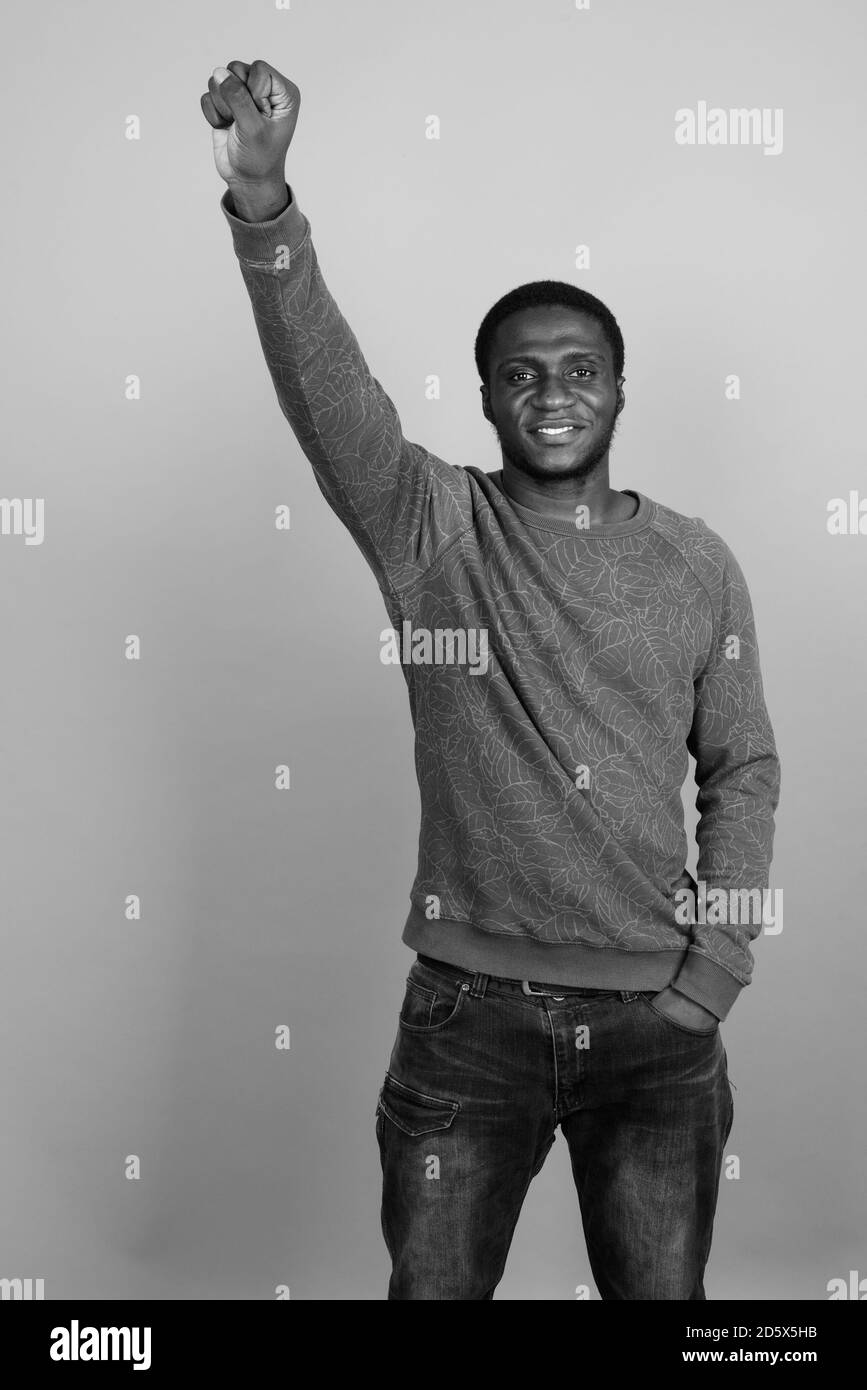 Junger afrikanischer Mann trägt langärmeliges Hemd vor grauem Hintergrund Stockfoto
