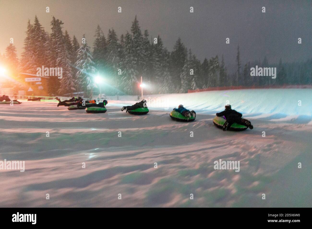 Eine Gruppe von Menschen rutscht in Oregon auf Rohren einen Schneehelz hinunter. Stockfoto