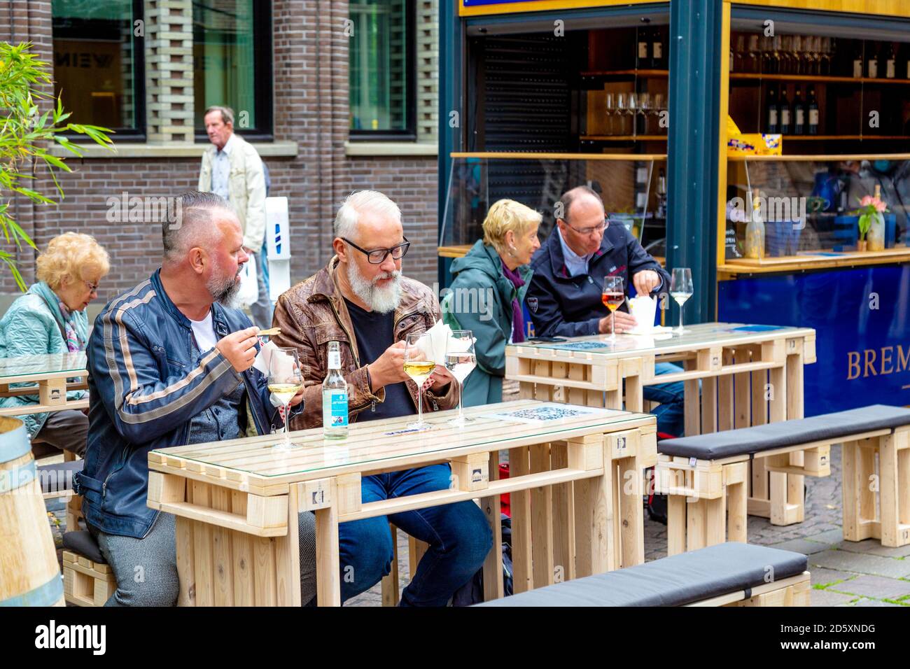 Menschen, die Wein trinken und im Freien am Weinkarton-Stand auf dem Marktplatz in Bremen essen Stockfoto