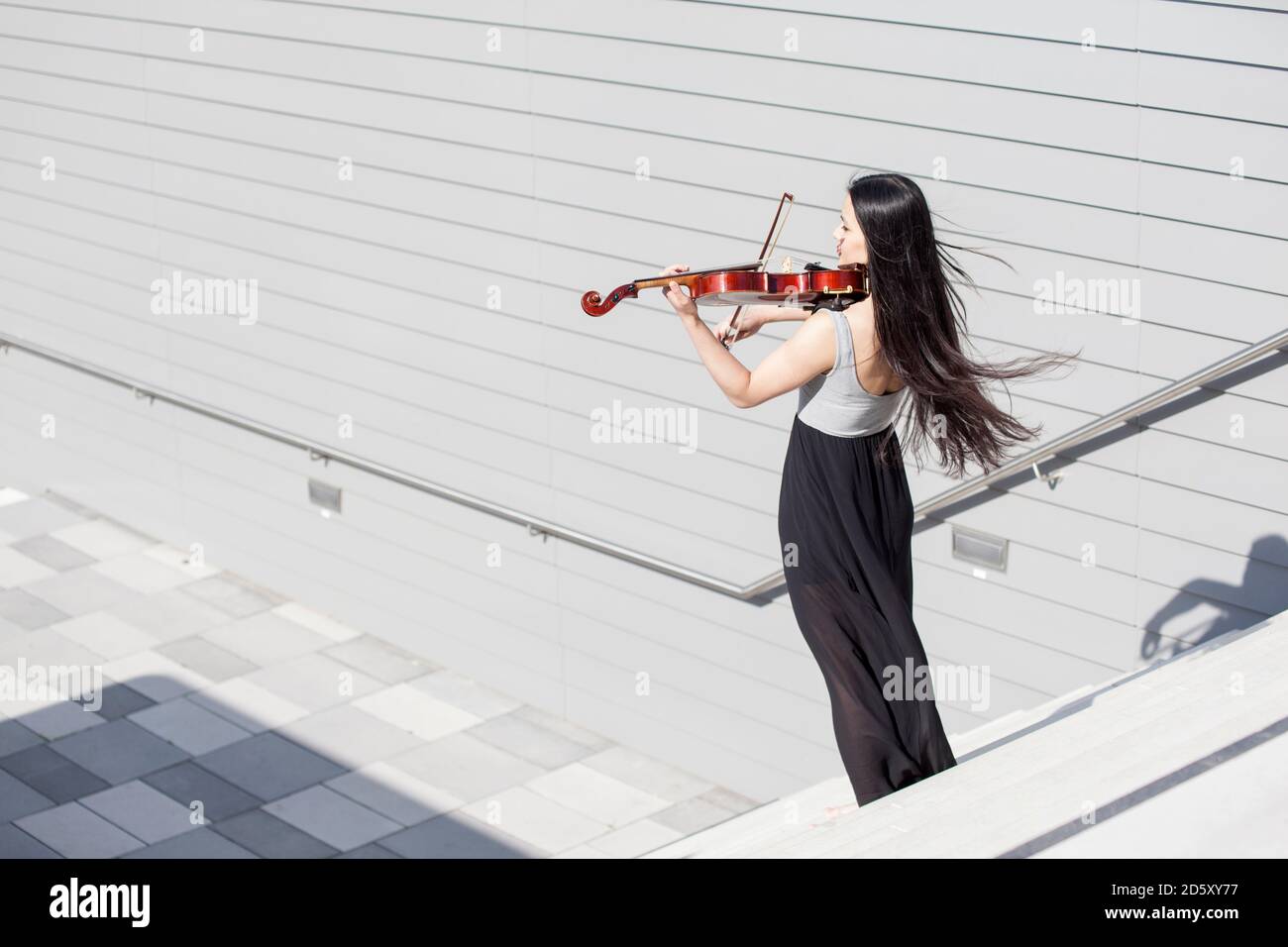 Junge weibliche asiatische spielen Geige auf Treppen Stockfoto