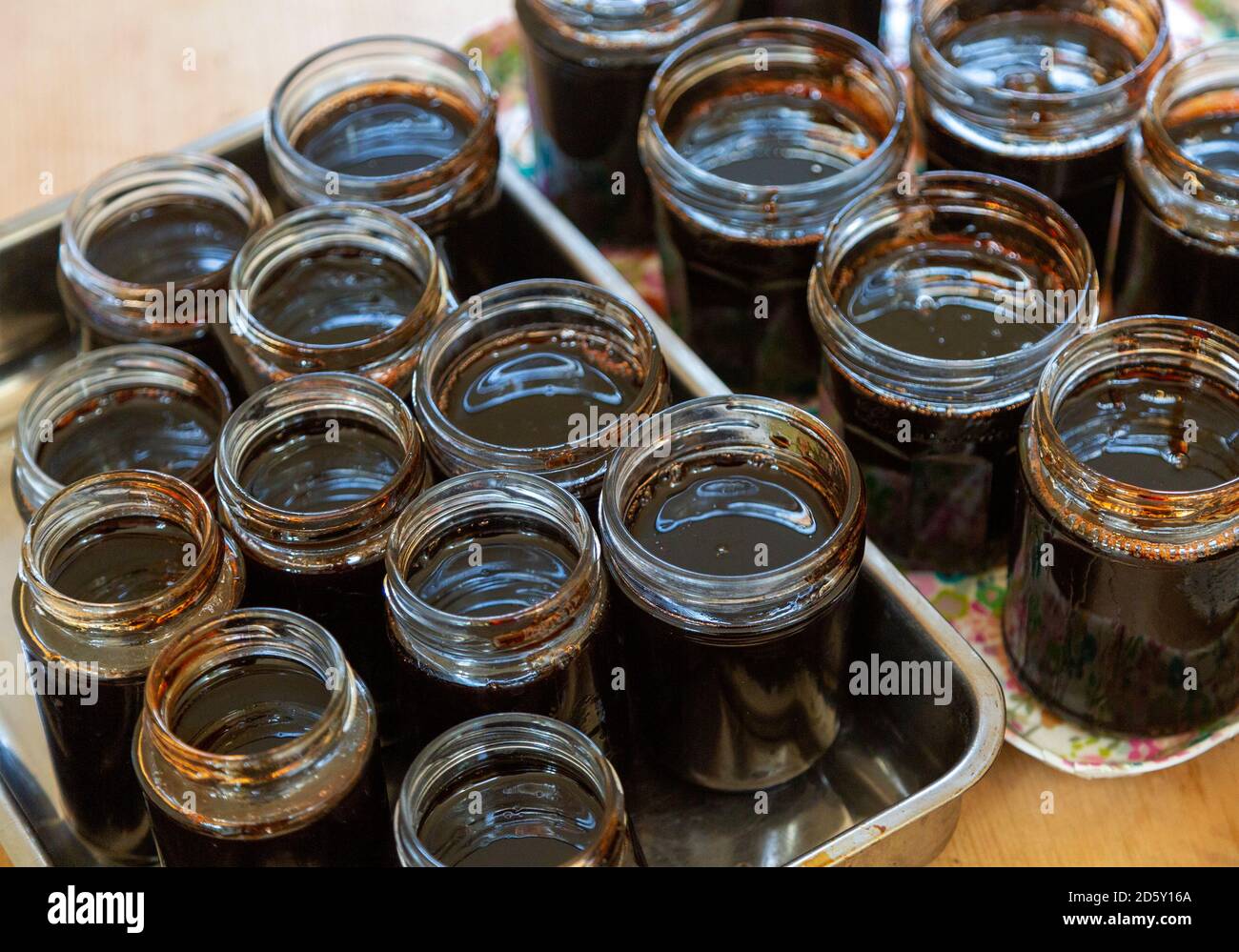 Offene Konfitüren Gläser gefüllt mit dunklen flüssigen Quitte Marmelade Gelee hausgemachte Konservierung Stockfoto
