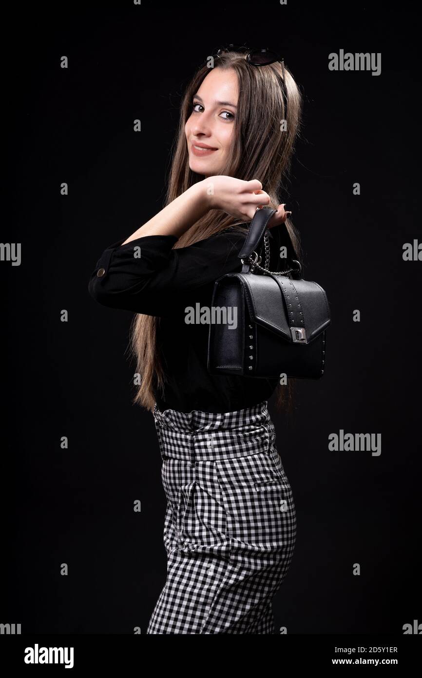 : schöne Frau mit Handtasche auf schwarzem Hintergrund Stockfoto