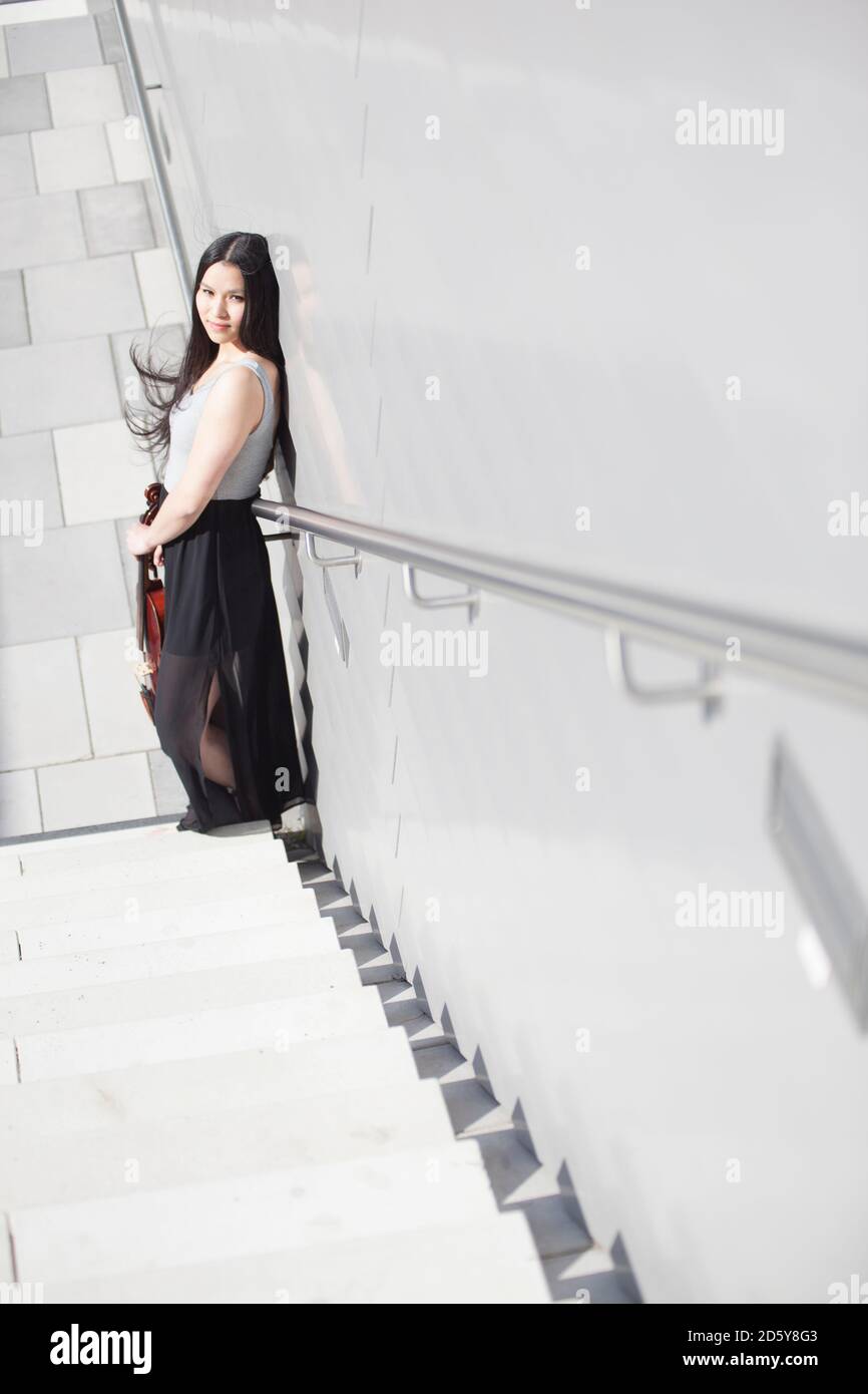 Junge weibliche asiatische mit Geige stehend auf der Treppe Stockfoto