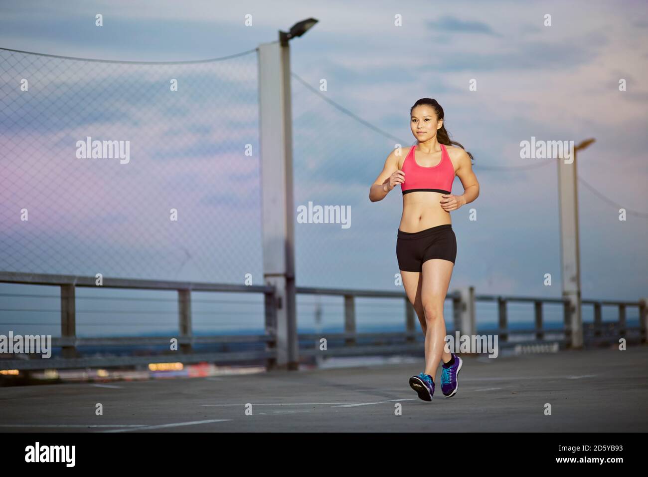 Junge weibliche asiatische Sportlerin Joggen in der Dämmerung Stockfoto